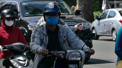 身穿黑色夹克、戴蓝色头盔的男子白天骑摩托车